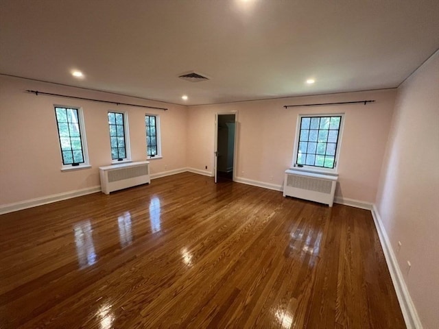 empty room with dark hardwood / wood-style floors and radiator