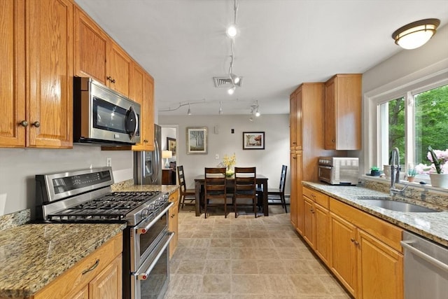 29 Day Ave, Hamilton, MA 01982 - kitchen featuring stainless steel appliances, a sink, light stone counters, track lighting, and brown cabinets