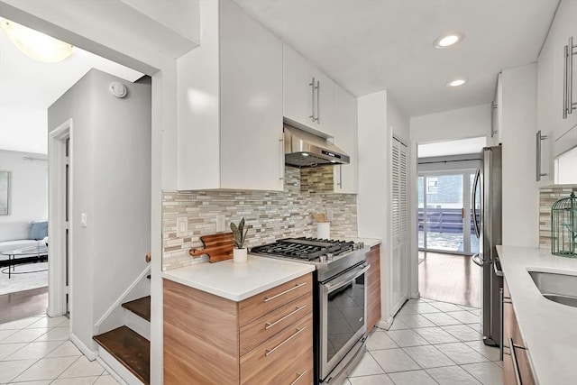 kitchen with decorative backsplash, light countertops, under cabinet range hood, stainless steel appliances, and light tile patterned flooring