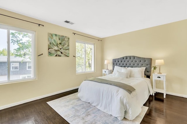 bedroom with baseboards, multiple windows, dark wood finished floors, and visible vents