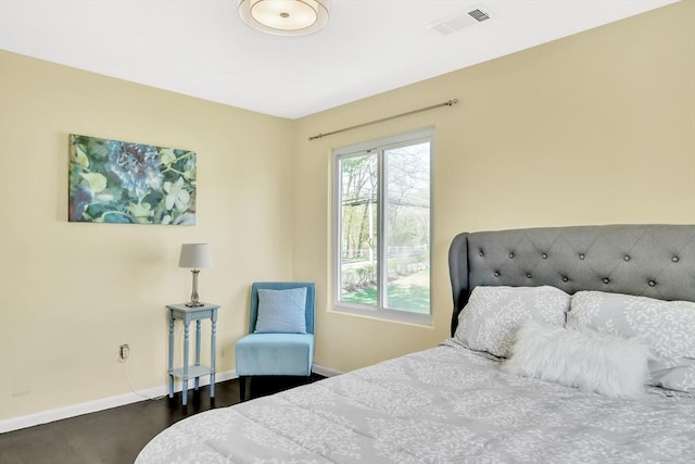 bedroom featuring visible vents, baseboards, and wood finished floors