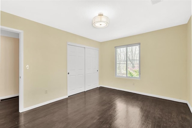unfurnished bedroom featuring baseboards, wood finished floors, and a closet