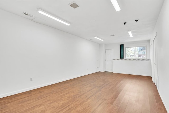 spare room featuring baseboards, wood finished floors, and visible vents