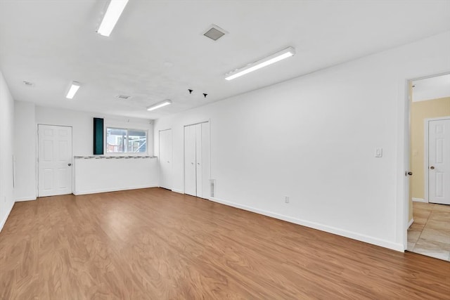 spare room with baseboards, visible vents, and wood finished floors