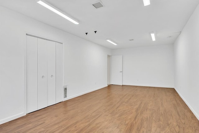 unfurnished room with baseboards, light wood-type flooring, and visible vents