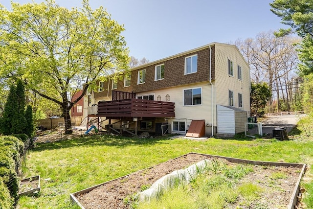 back of house with a lawn, fence, a vegetable garden, and a deck