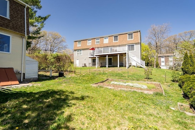 back of property with stairway, a garden, a yard, and a deck