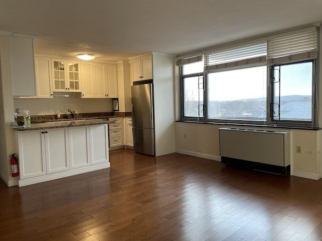 kitchen with dark wood-style floors, white cabinetry, freestanding refrigerator, radiator, and glass insert cabinets