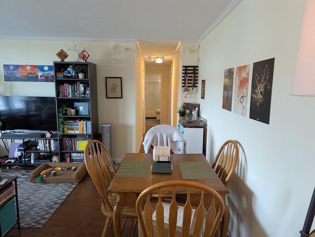 dining space with wood finished floors and crown molding