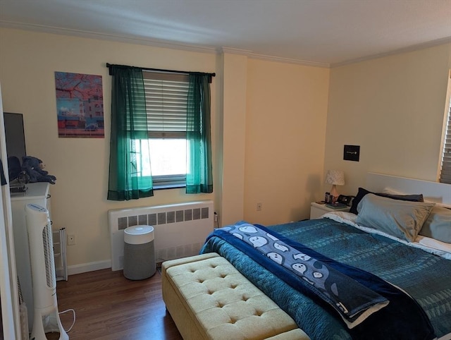 bedroom featuring radiator heating unit, wood finished floors, baseboards, and ornamental molding