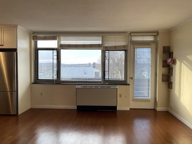 interior space featuring baseboards, radiator heating unit, dark wood-style flooring, freestanding refrigerator, and ornamental molding