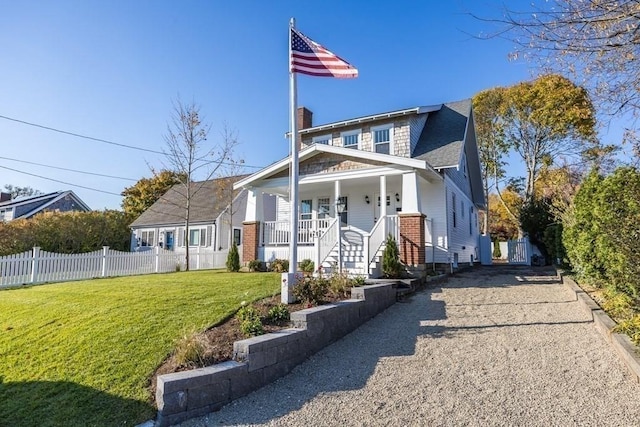 bungalow-style home featuring a front lawn, fence, roof with shingles, covered porch, and a chimney