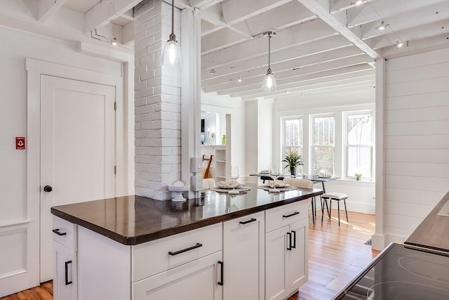 kitchen with wood counters, light wood-style floors, hanging light fixtures, and white cabinetry