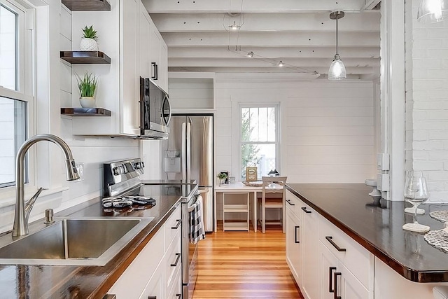 kitchen with a sink, open shelves, dark countertops, and stainless steel appliances