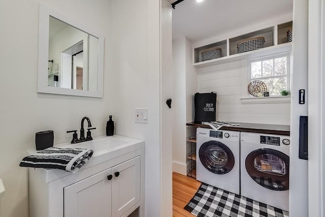 laundry area with a sink, laundry area, light wood-type flooring, and separate washer and dryer