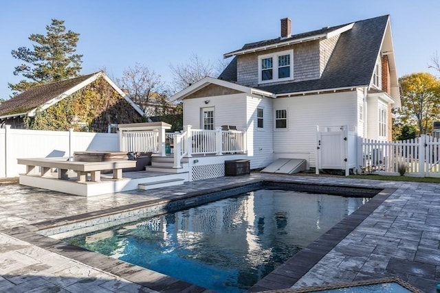 rear view of house with a fenced in pool, a fenced backyard, a chimney, and a wooden deck