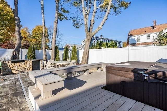 deck featuring outdoor dining space, a fenced backyard, and a hot tub