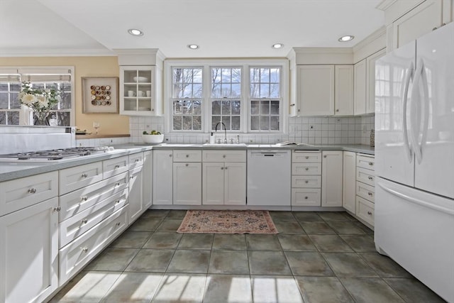 kitchen with white appliances, white cabinets, backsplash, and a sink