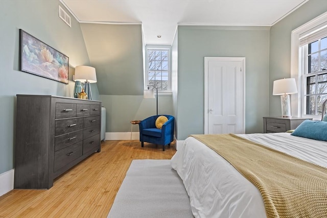 bedroom featuring light wood-type flooring, visible vents, baseboards, and crown molding