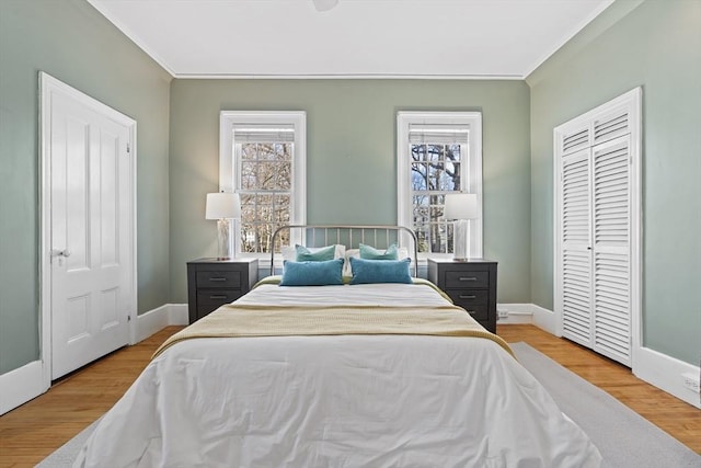 bedroom featuring multiple windows, ornamental molding, baseboards, and wood finished floors