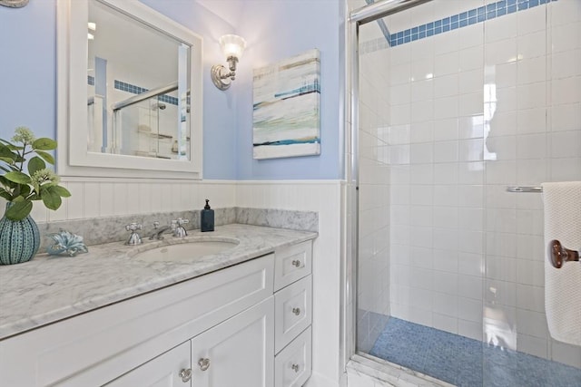 bathroom featuring vanity, a shower stall, and a wainscoted wall