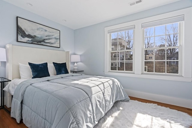 bedroom featuring visible vents, baseboards, and wood finished floors