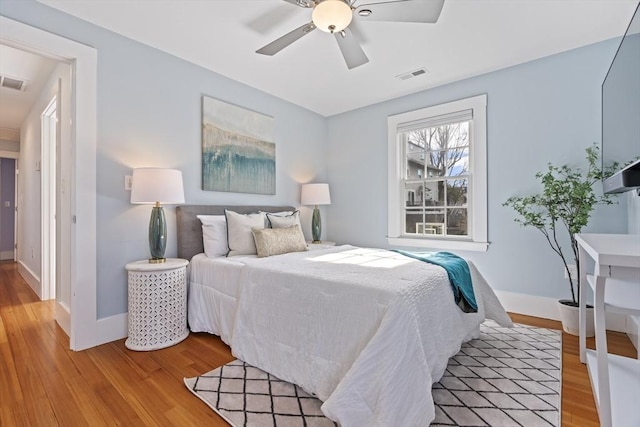 bedroom featuring baseboards, visible vents, light wood finished floors, and ceiling fan