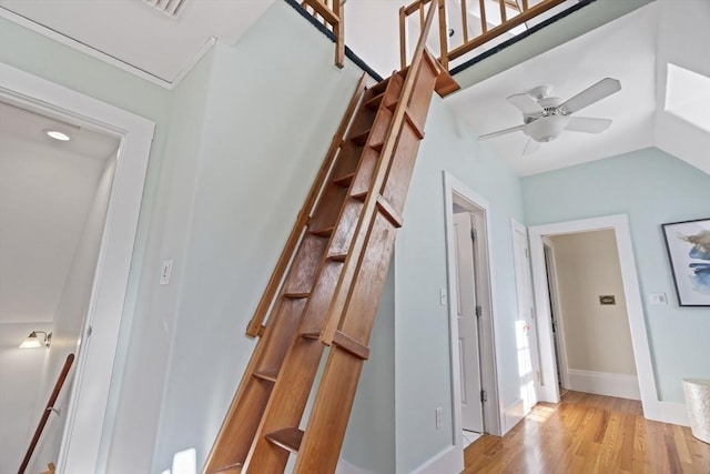 hall featuring light wood-style flooring, baseboards, and vaulted ceiling