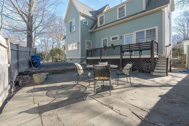 back of property with outdoor dining space, a patio, fence, a shingled roof, and a wooden deck