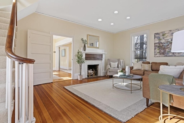 living area with stairway, recessed lighting, a fireplace with flush hearth, and wood finished floors