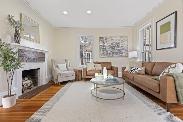 living area featuring plenty of natural light, ornamental molding, a fireplace, and wood finished floors