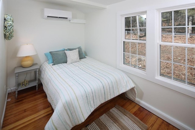 bedroom with a wall unit AC, multiple windows, and wood finished floors