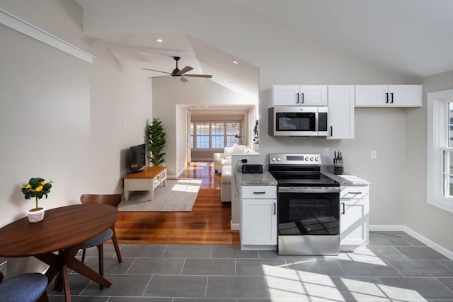 kitchen featuring vaulted ceiling, white cabinets, baseboards, and appliances with stainless steel finishes