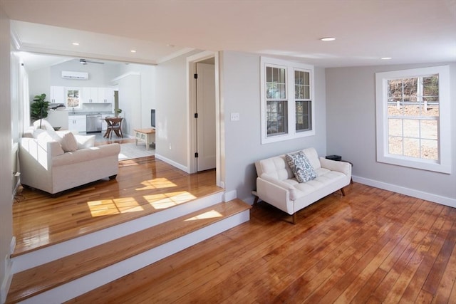 living area with hardwood / wood-style floors, recessed lighting, baseboards, and a wall mounted AC