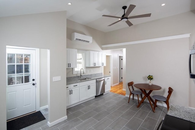 kitchen with light stone countertops, a wall mounted air conditioner, stainless steel dishwasher, white cabinetry, and a sink