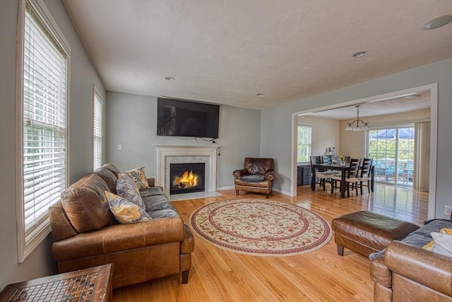 living room with wood finished floors, a fireplace with flush hearth, recessed lighting, and a chandelier