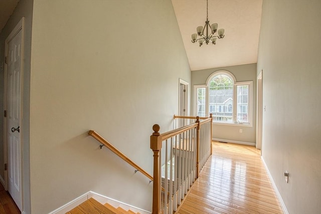 stairs with a chandelier, hardwood / wood-style floors, baseboards, and high vaulted ceiling