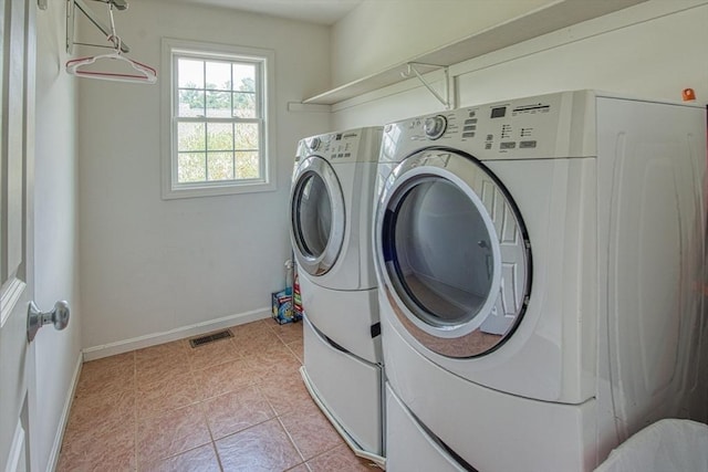 laundry area featuring washing machine and clothes dryer, baseboards, and light tile patterned floors