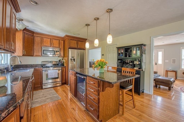 kitchen with appliances with stainless steel finishes, beverage cooler, a sink, and brown cabinetry