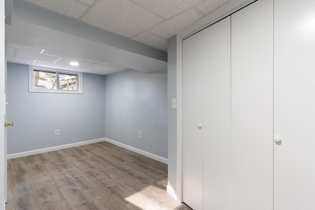 basement with a drop ceiling and light hardwood / wood-style floors