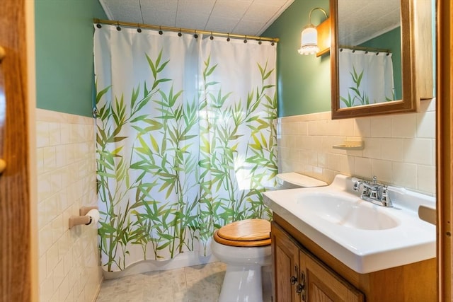 bathroom featuring tile walls, toilet, curtained shower, and vanity