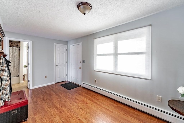 24 Shore Rd, Southwick, MA 01077 - foyer featuring a baseboard heating unit, light wood-style floors, a textured ceiling, and baseboards