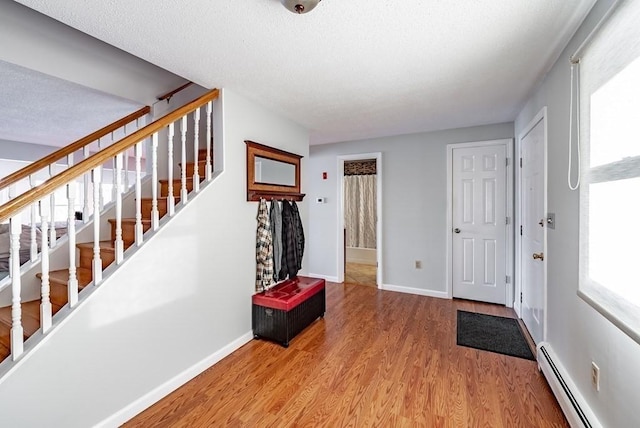 24 Shore Rd, Southwick, MA 01077 - foyer featuring a baseboard heating unit, wood finished floors, stairway, baseboards, and a textured ceiling