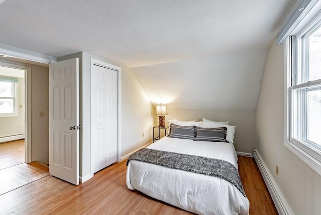 24 Shore Rd, Southwick, MA 01077 - bedroom with baseboard heating, light wood-style flooring, a closet, a textured ceiling, and vaulted ceiling