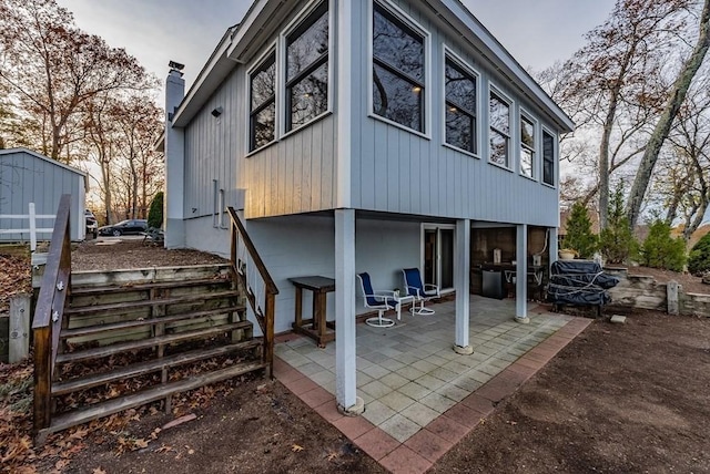 24 Shore Rd, Southwick, MA 01077 - back of house featuring a patio, a storage shed, an outdoor structure, a chimney, and board and batten siding