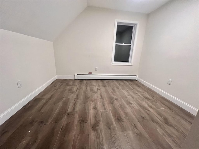 additional living space with dark wood-type flooring, a baseboard radiator, and lofted ceiling