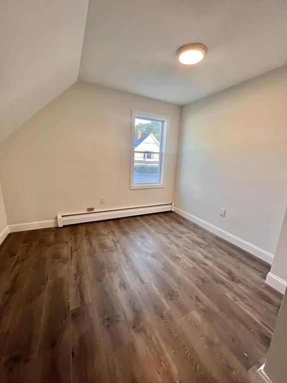 additional living space featuring lofted ceiling, a baseboard radiator, and dark hardwood / wood-style floors