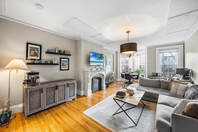 living area featuring baseboards, light wood-style floors, and ornamental molding