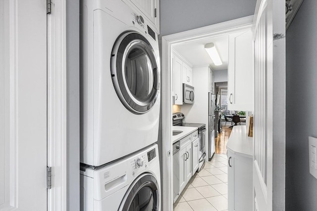 clothes washing area featuring stacked washer / drying machine, light tile patterned floors, and laundry area