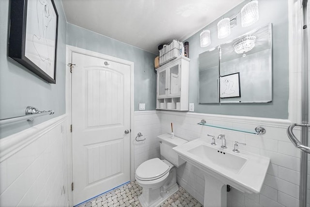 bathroom with tile walls, tile patterned floors, a wainscoted wall, and toilet